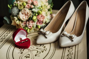 Güzel bir kırmızı kutu nikah yüzükleri buket ve ayakkabı gelinin yanında masada yalan