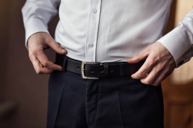 İş adamı kemer takıyor, moda ve giysi konsepti, damat törenden önce sabah hazırlanıyor.