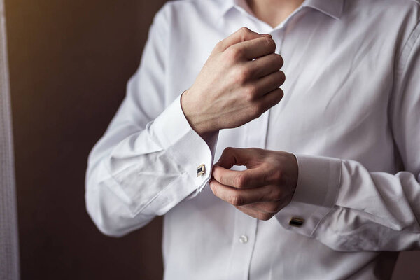 Businessman dresses white shirt, male hands closeup,groom getting ready in the morning before wedding ceremony