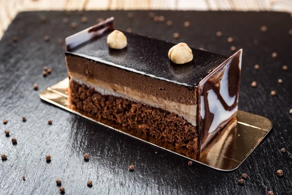 Dark chocolate vegan cake with candies and nuts on wooden background