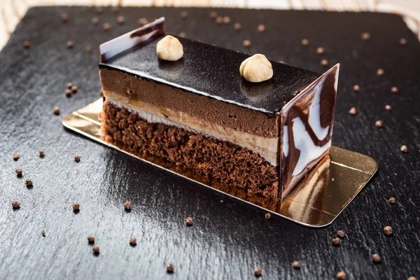 Dark chocolate vegan cake with candies and nuts on wooden background