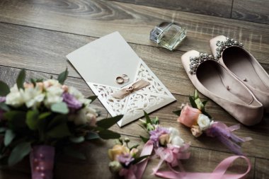 Ayakkabı, davetiye, yüzük, parfüm, buket gibi gelin aksesuarları bir ahşap arka plan üzerinde yalan