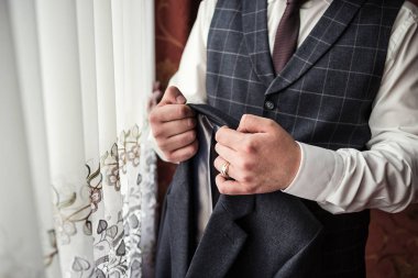 İş adamı ceket giyiyor, erkek eli kapalı, damat düğün töreninden önce hazırlanıyor.