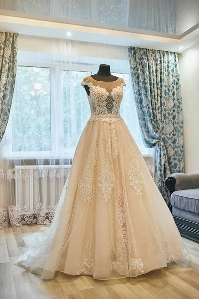 beautiful wedding dress hanging in the room, woman getting ready before  ceremony