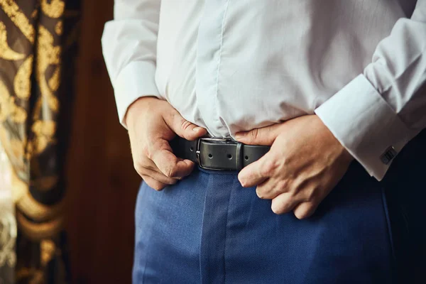 Businessman putting on a belt, fashion and clothing concept,groom getting ready in the morning before ceremony