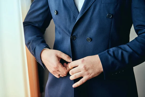 El hombre de negocios lleva una chaqueta, las manos masculinas se acercan, el novio se prepara en la mañana antes de la ceremonia de boda. Moda de hombres —  Fotos de Stock