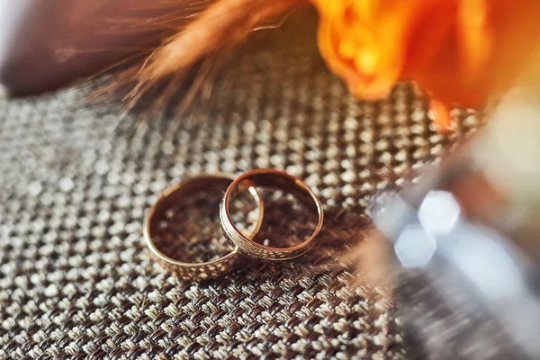 Anillos de boda se encuentran en la mesa cerca de un ramo de bodas — Foto de Stock