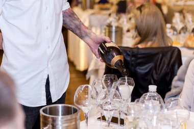 Garson şampanya beyaz masanın üzerine bir bardak içine dökülen