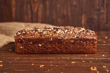 Ahşap arka planda tüm buğday zanaat ekmek. Sağlıklı gıda ve geleneksel fırın kavramı. Rustik