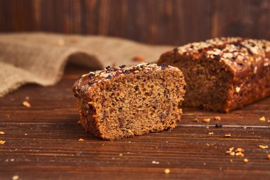 Ahşap arka planda tüm buğday zanaat ekmek. Sağlıklı gıda ve geleneksel fırın kavramı. Rustik