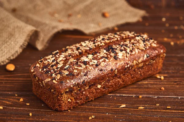 Ahşap arka planda tüm buğday zanaat ekmek. Sağlıklı gıda ve geleneksel fırın kavramı. Rustik