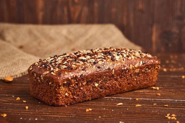 Ahşap arka planda tüm buğday zanaat ekmek. Sağlıklı gıda ve geleneksel fırın kavramı. Rustik