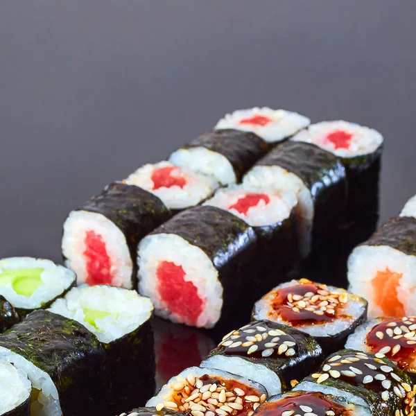 Various kinds of tasty sushi roll on black background for menu. Japanese food