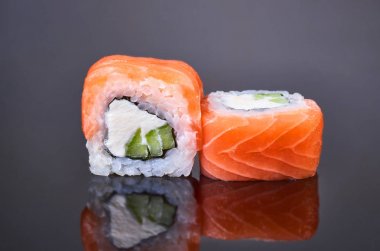 Menü için siyah arka plan üzerinde somon, avokado ve krem peynir ile Philadelphia rulo suşi. Japon yemekleri