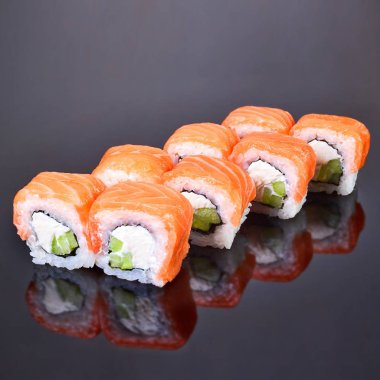 Menü için siyah arka plan üzerinde somon, avokado ve krem peynir ile Philadelphia rulo suşi. Japon yemekleri