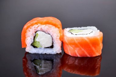 Menü için siyah arka plan üzerinde somon, avokado ve krem peynir ile Philadelphia rulo suşi. Japon yemekleri