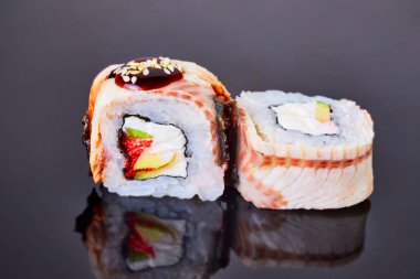 Menü için siyah arka plan üzerinde füme geyik balığı, avokado, ton balığı ve krem peynir ile Philadelphia rulo suşi. Japon yemekleri