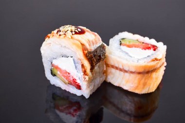 Menü için siyah arka plan üzerinde füme geyik balığı, avokado, ton balığı ve krem peynir ile Philadelphia rulo suşi. Japon yemekleri