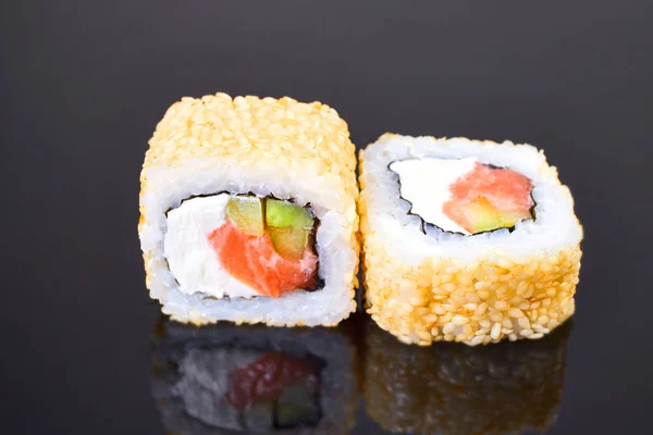 California roll sushi con sésamo, salmón, aguacate y queso crema sobre fondo negro para el menú. Comida japonesa —  Fotos de Stock