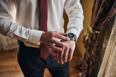 İş adamı kol saatini kontrol ediyor, saati eline alıyor, damat düğün töreninden önce hazırlanıyor. Erkekler Moda