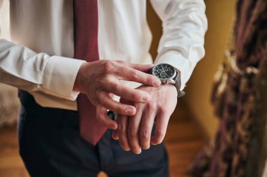 İş adamı kol saatini kontrol ediyor, saati eline alıyor, damat düğün töreninden önce hazırlanıyor. Erkekler Moda