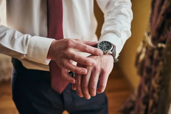 Uomo d'affari che controlla l'ora sul suo orologio da polso, uomo che mette l'orologio a portata di mano, sposo che si prepara la mattina prima della cerimonia nuziale. Moda uomo — Foto Stock