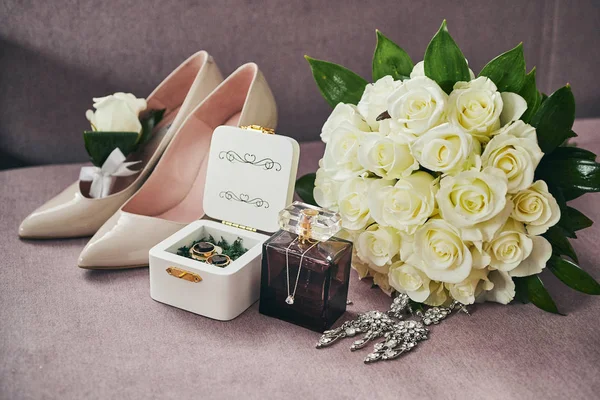 bridal accessories such as shoes, bouquet , ring and perfume lie on a table