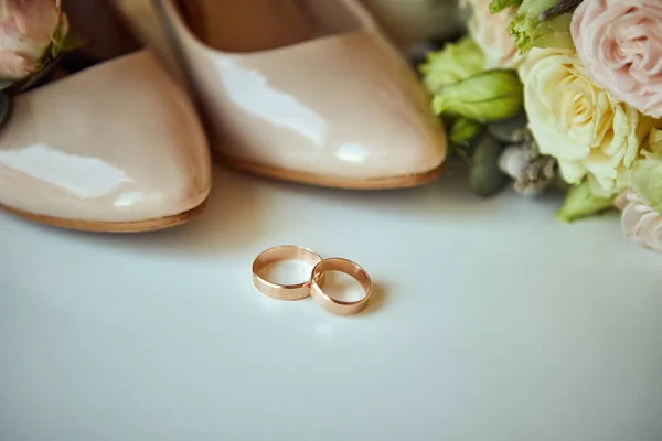 Anillos de boda se encuentran en la mesa cerca de un ramo de bodas — Foto de Stock