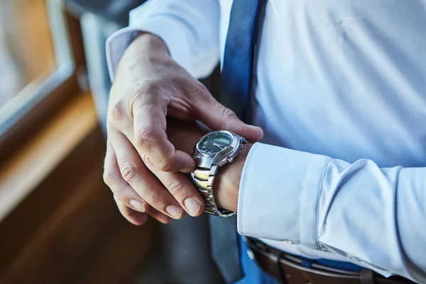 Affärsman kollar tiden på handleden, man sätter klockan på hand, brudgummen gör sig redo på morgonen före bröllopsceremonin. Män mode — Stockfoto