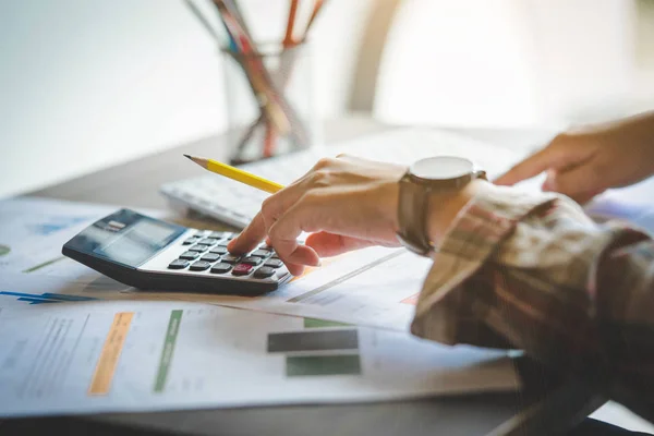 Businesswoman hands holding pencil working  with calculator for calculate business profits turnover business. Business financial analysis and strategy concept.