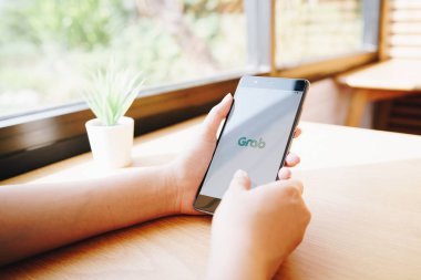 Chiang Mai, Tayland - Ocak 19,2019: Kepçe apps üstünde perde ile Huawei tutan kadın. Akıllı telefon app tüm-içinde-bir taşıma rezervasyon Güney-Doğu Asya kapmak olduğunu.