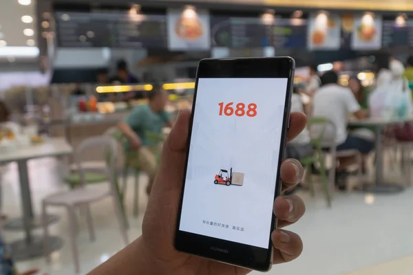 CHIANG MAI, TAILANDIA - ENERO. 06,2019: Hombre sosteniendo HUAWEI con 1688 aplicaciones en la pantalla.1688.com también llamado Alibaba.cn es la versión china popular de Alibaba.com . — Foto de Stock