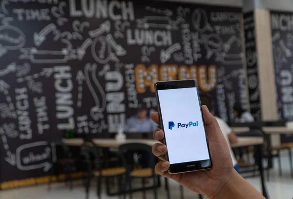 CHIANG MAI, TAILANDIA - ENERO. 06,2019: Hombre sosteniendo HUAWEI con aplicaciones PayPal en la pantalla. PayPal es un sistema de pago electrónico en línea . — Foto de Stock