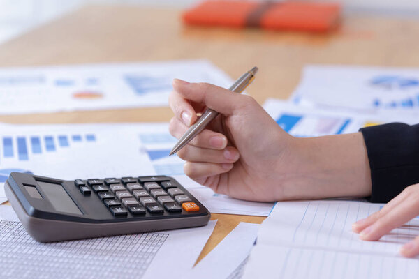 Woman entrepreneur using a calculator to calculating financial expense at office.