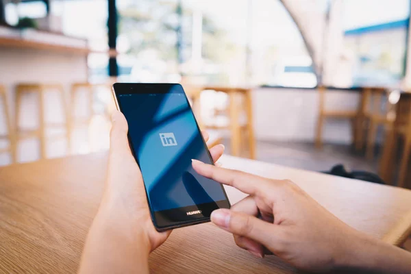 CHIANG MAI, TAILANDIA - ENERO. 19,2019: Mujer sosteniendo el teléfono móvil HUAWEI con la aplicación Linkedin en la pantalla. Linkedin es un servicio de redes sociales orientado a las empresas y el empleo . — Foto de Stock