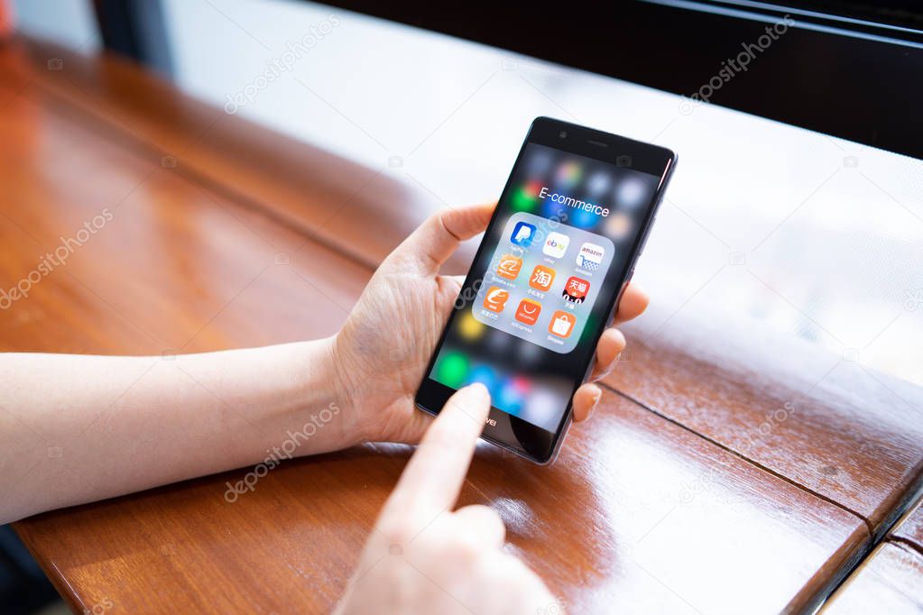CHIANG MAI, THAILAND - FEB. 18,2019: Woman holding HUAWEI with icons of E-commerce and online shopping on screen.smartphone lifestyle,e-commerce app concept.