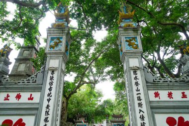 Ngoc Son Tapınağı 'nın Hanoi, Vietnam' daki Hoan kiem gölündeki girişi. Yeşilliğin ortasında yuva yapmış Ngoc Son Tapınağı girişi Hoan Kiem Gölü, Hanoi, Vietnam 'a bakıyor. Yapıda geleneksel Vietnam mimari unsurları yer alıyor. 