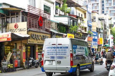 Hanoi 'deki sokak sahnesinde yerel dükkanlar, insanlar, scooterlar ve araçlar var. Hanoi, Vietnam, Temmuz 2025