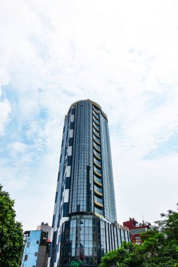 Yansıtıcı cam cepheli modern binalar. Yapıda klasik ve çağdaş stillerin birleştirildiği dekoratif mimari ayrıntılar yer alıyor. Hanoi, Vietnam, Temmuz 2025