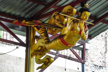 2025 'te Yeşim İmparatoru Pagoda, Ho Chi Minh City, Vietnam' da bulunan kırmızı kirişlerle desteklenen kıvrımlı metal bir çatının altına yerleştirilmiş altın bir tanrı heykeli.