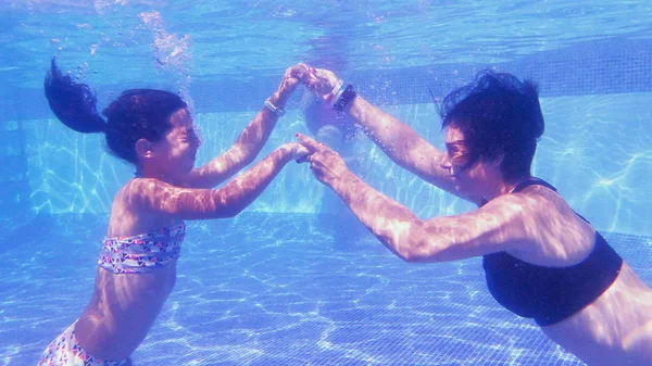 Mãe e filha mergulhando em uma piscina — Fotografia de Stock