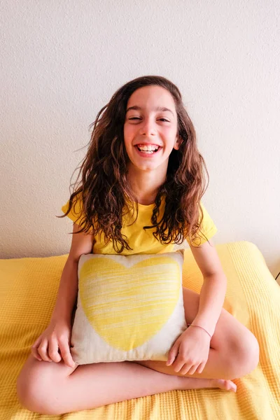 Chica riendo y abrazando un cojín con el corazón amarillo dibujado — Foto de Stock