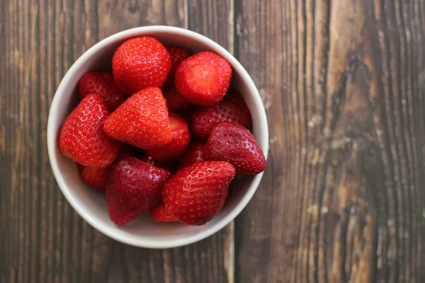 Top view strawberries in bowl on wood background — Stock Photo, Image