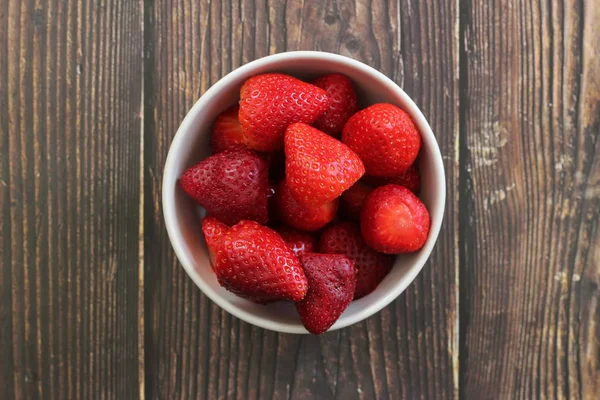 Top view strawberries in bowl on wood background — Stock Photo, Image