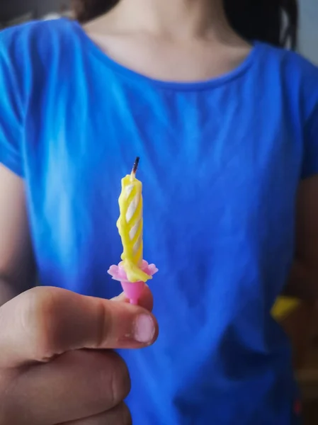 Рука маленькой девочки держит желтые спиральные свечи на день рождения — стоковое фото