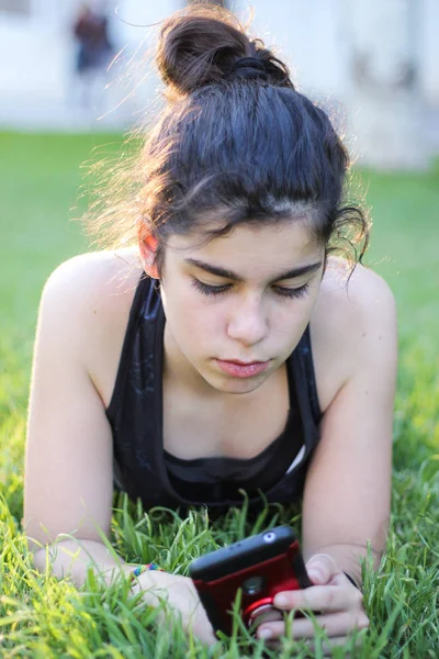 Remaja bersantai di rumput dan menonton mobile selama istirahat setelah pelatihan — Stok Foto