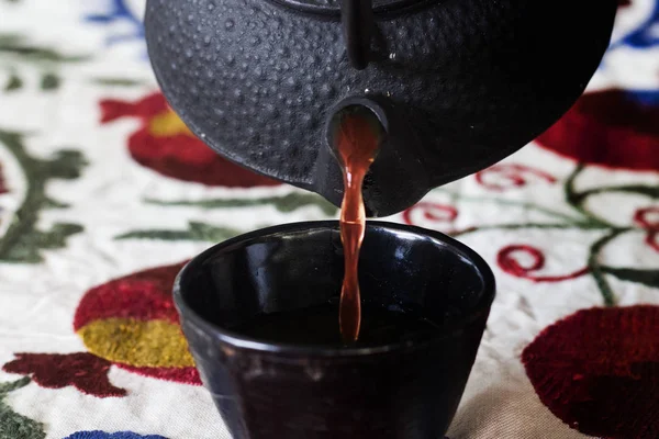 Verter el té de una tetera en una taza de té — Foto de Stock