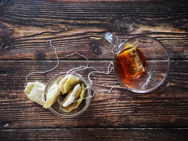 Infusor con bolsas de té usadas en mesa de madera negra — Foto de Stock