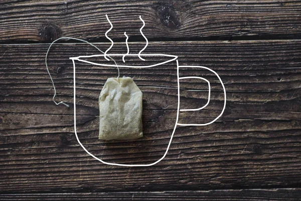 Bolsa de té usada y una taza dibujada en la mesa de madera — Foto de Stock