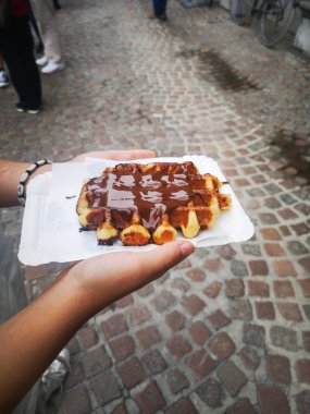 Bruges bir sokakta bir çikolata waffle tutan bir kızın eli